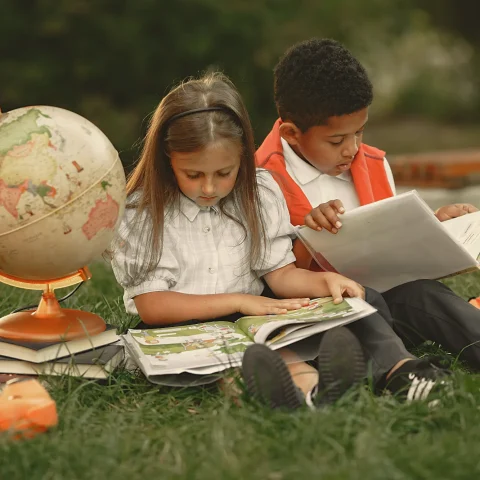 Two children reading on the grass